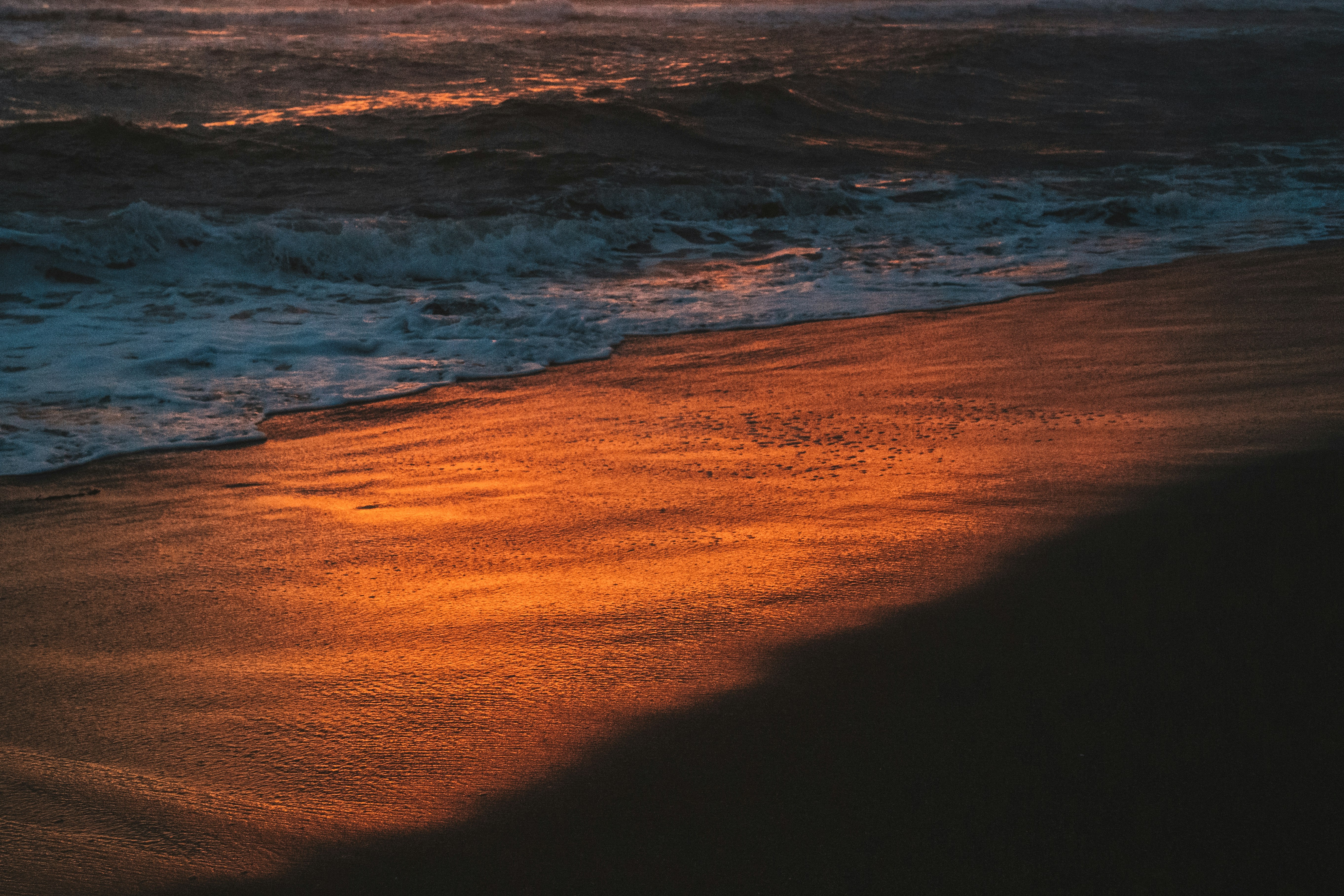 ocean waves crashing on shore during sunset